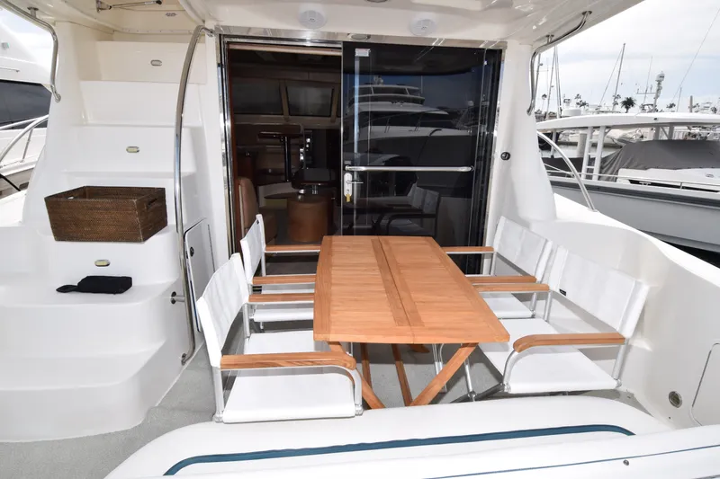 Slide: The Image of Outdoor seating area on 2005 Sea Ray 500 Sedan Bridge yacht with wooden table and chairs. - 24