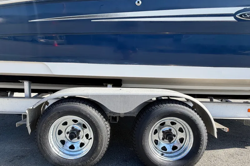 Slide: The Image of 2008 Sea Ray 240 Sundeck on trailer, showcasing sleek blue hull and dual wheels. - 95