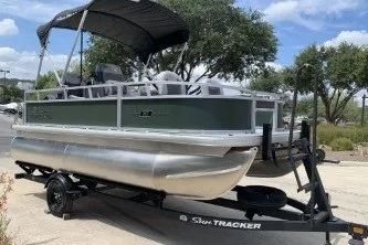 The Image of 2027 Sun Tracker Bass Buggy 16 XL Select pontoon boat on trailer, outdoors. - 0
