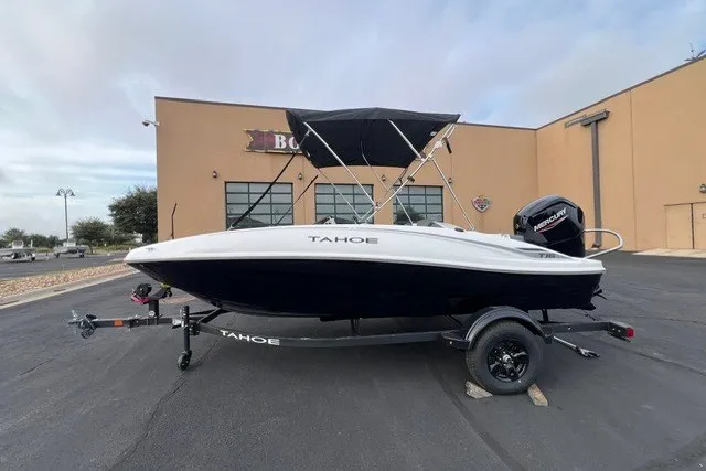 The Image of 2027 Tahoe T16 boat with canopy on trailer, parked outside a building. - 0
