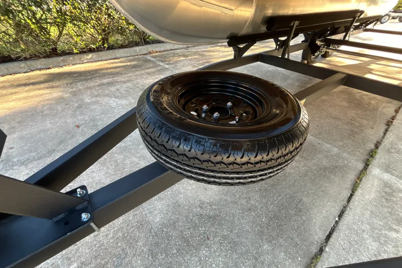 Slide: The Image of 2027 Sun Tracker SportFish 20 DLX trailer with spare tire on concrete surface. - 39
