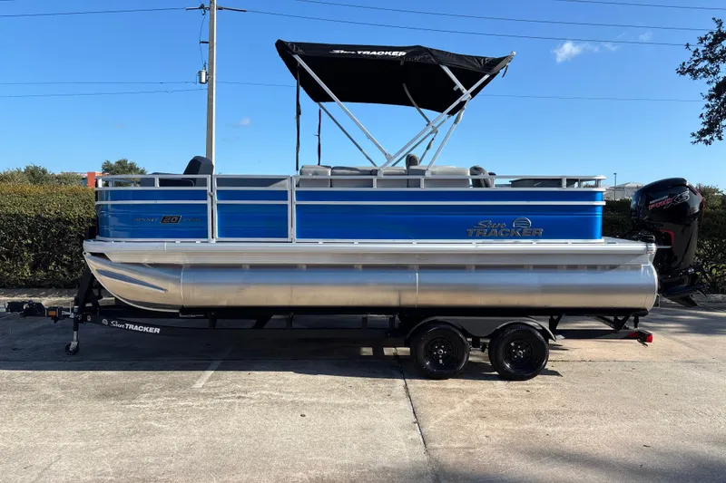 The Image of 2027 Sun Tracker SportFish 20 DLX pontoon boat with blue exterior and black canopy. - 0
