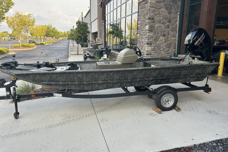 The Image of 2027 Tracker Grizzly 1648 SC boat on trailer, parked outside a building. - 0