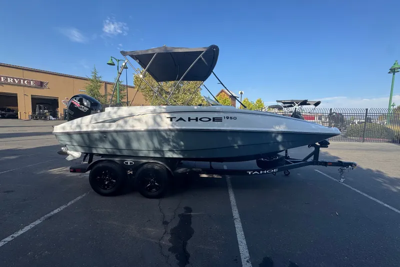Slide: The Image of 2027 Tahoe 1950 boat on trailer in parking lot, under clear blue sky. - 4