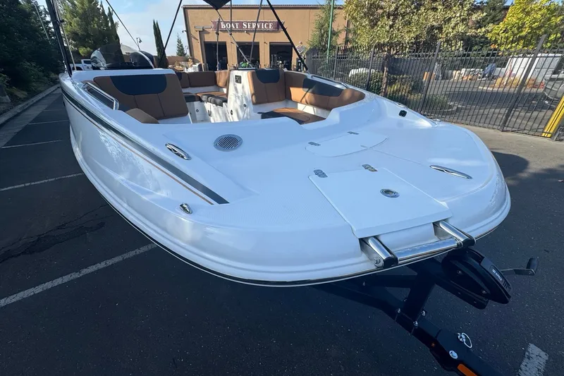 Slide: The Image of 2027 Tahoe 1950 boat with sleek white design and brown seating, parked near a service center. - 9