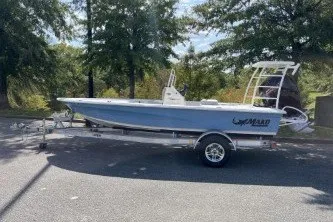 The Image of 2026 Mako 18 Pro Skiff boat on trailer, parked outdoors with trees in background. - 0
