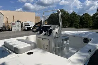 Slide: The Image of 2026 Mako 18 Pro Skiff boat with console, parked outdoors under a cloudy sky. - 5