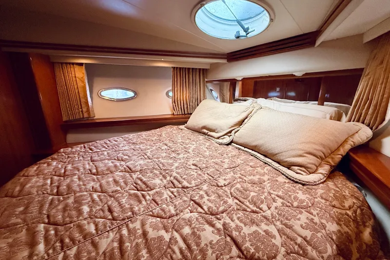 Slide: The Image of Luxurious bedroom interior of 2005 Carver 56 Voyager yacht with elegant bedding and porthole windows. - 46