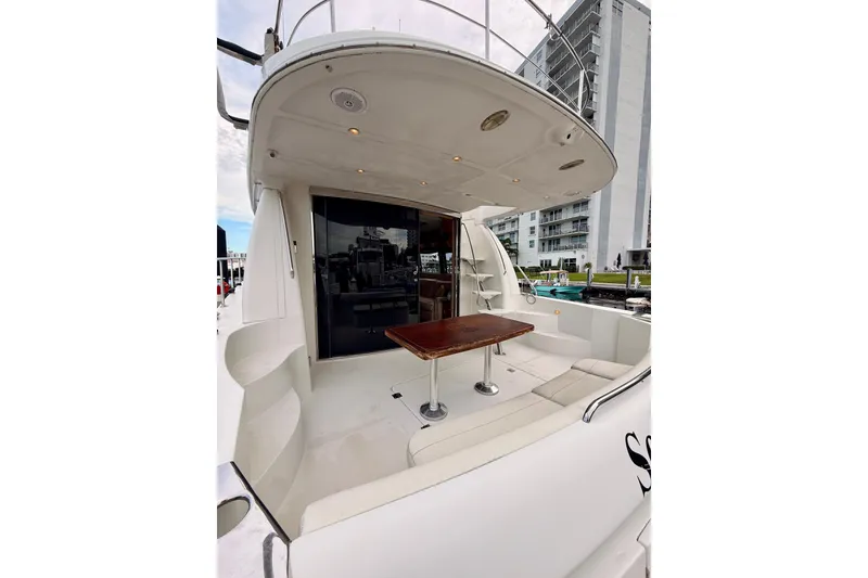 Slide: The Image of 2005 Carver 56 Voyager yacht deck with seating and table, docked near modern buildings. - 7