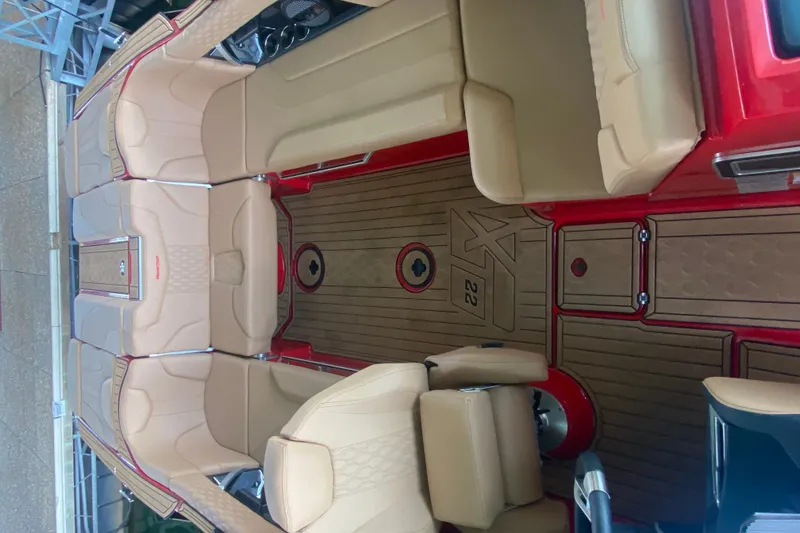 Slide: The Image of 2024 MasterCraft XT22 boat interior with beige seating and red accents. - 6