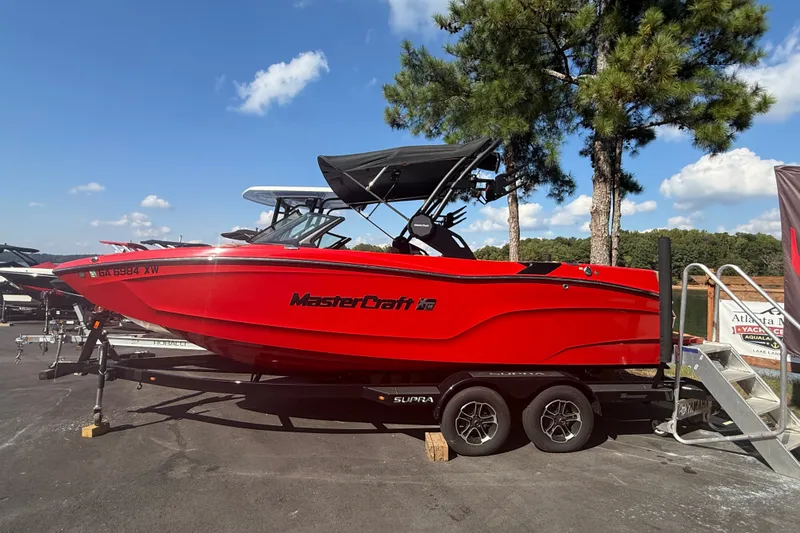 Slide: The Image of 2024 MasterCraft XT22 boat in vibrant red on a trailer, parked outdoors. - 14