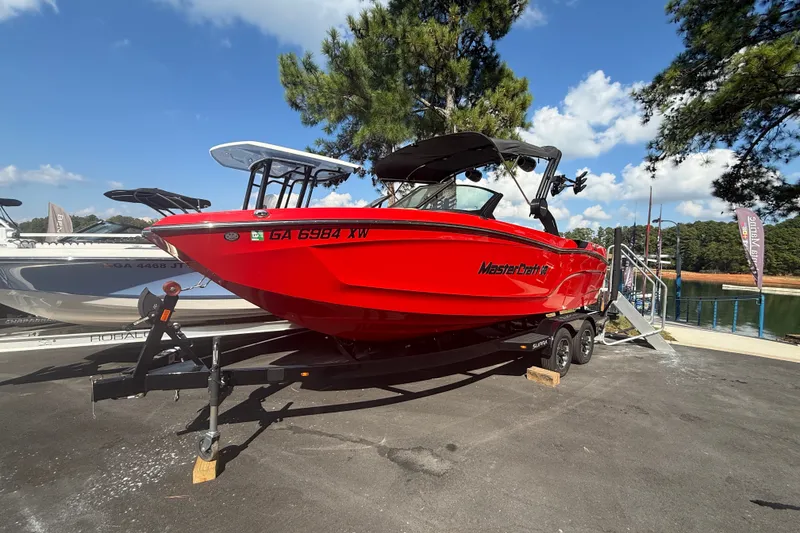 Slide: The Image of 2024 MasterCraft XT22 boat in vibrant red on a trailer, parked outdoors. - 13