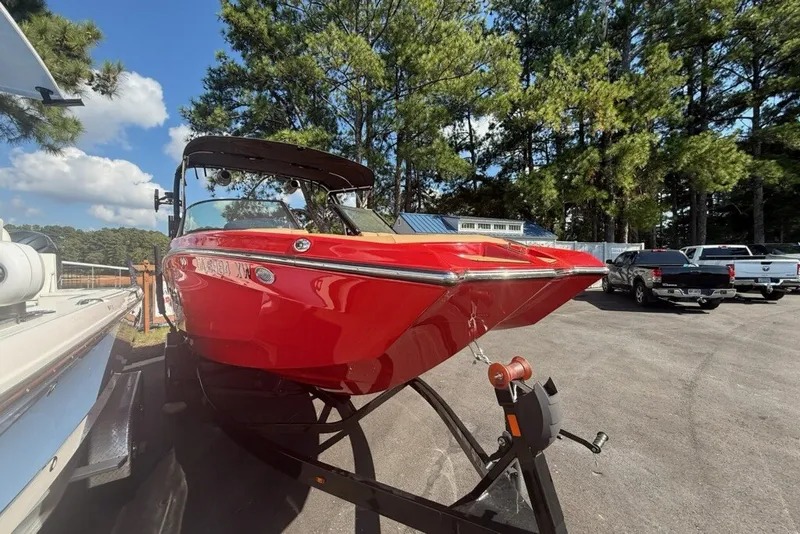 Slide: The Image of 2024 MasterCraft XT22 boat in vibrant red, parked outdoors under a clear sky. - 18