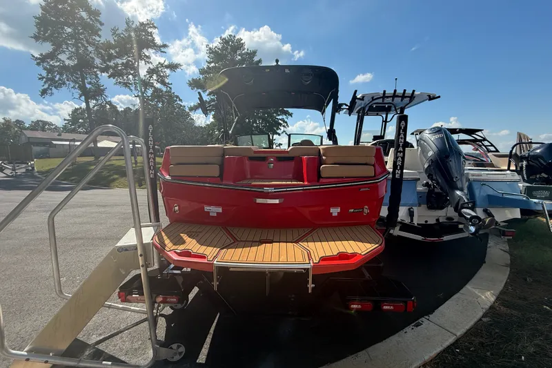 Slide: The Image of 2024 MasterCraft XT22 boat with red exterior and wooden deck, parked outdoors. - 16