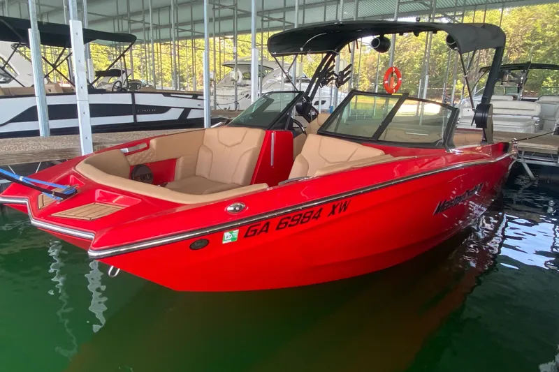 Slide: The Image of 2024 MasterCraft XT22 boat in vibrant red docked in a marina. - 1