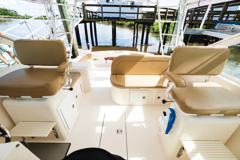 Slide: The Image of Interior view of a 2006 Carolina Classic 32 boat with beige seating and dockside background. - 23