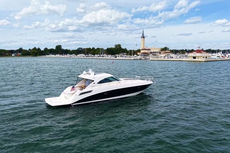 The Image of 2010 Sea Ray Sundancer 540 yacht cruising near a marina under a partly cloudy sky. - 0