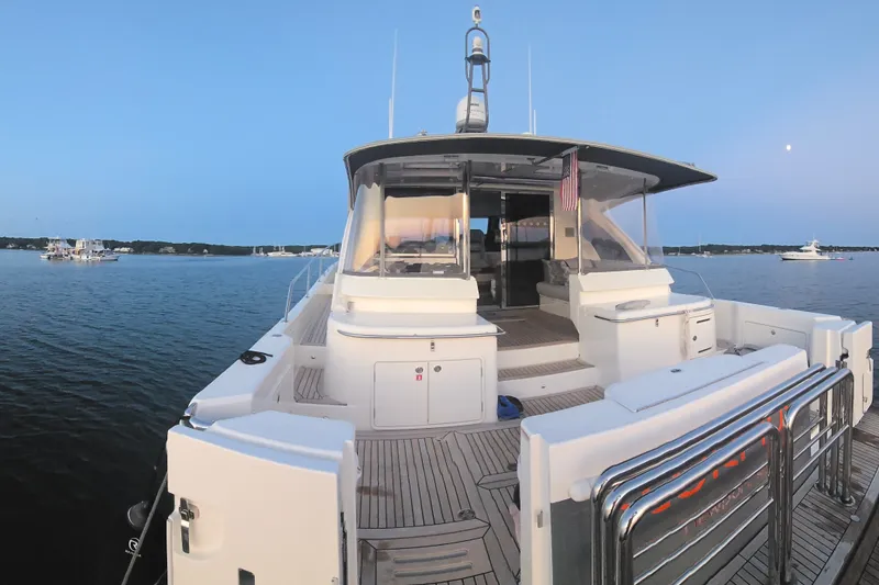 Slide: The Image of 2022 Riviera 505 SUV yacht on calm water at sunset, showcasing spacious deck and sleek design. - 82