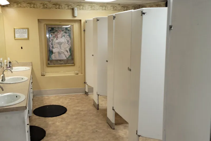 Slide: The Image of Restroom with white stalls, sinks, and decorative wall art, Custom Dinner Excursion Passenger, 1985. - 8