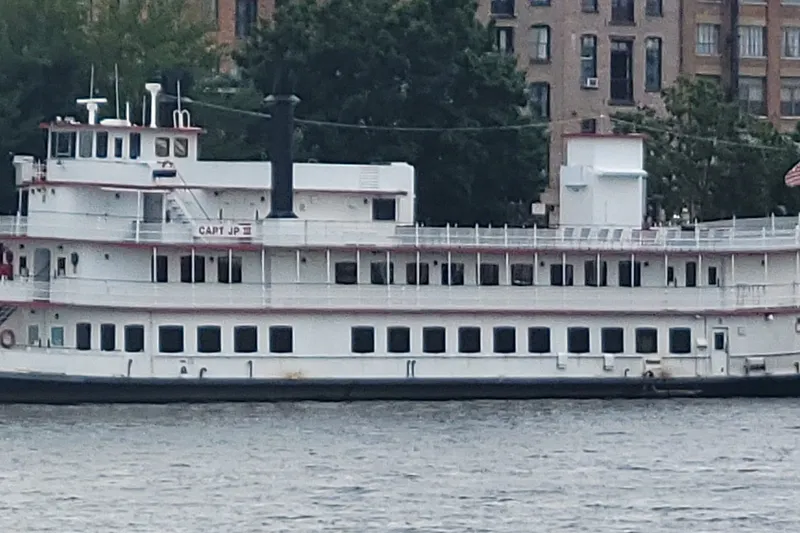 Slide: The Image of Vintage 1985 custom dinner excursion passenger boat on a river, with cityscape backdrop. - 1