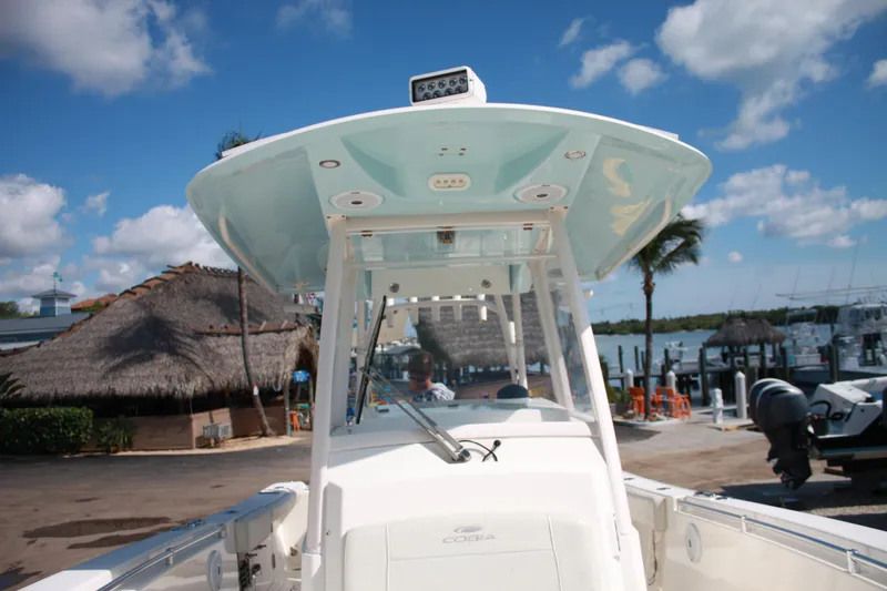 Slide: The Image of 2018 Cobia 301 Center Console with T-top, docked with palm trees in the background. - 42