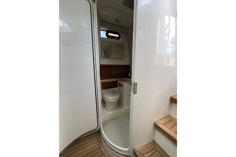 Slide: The Image of Interior view of 2023 Boston Whaler 420 Outrage boat bathroom with wooden accents. - 29