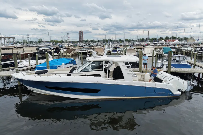 The Image of 2023 Boston Whaler 420 Outrage docked at a marina, featuring sleek blue and white design. - 1