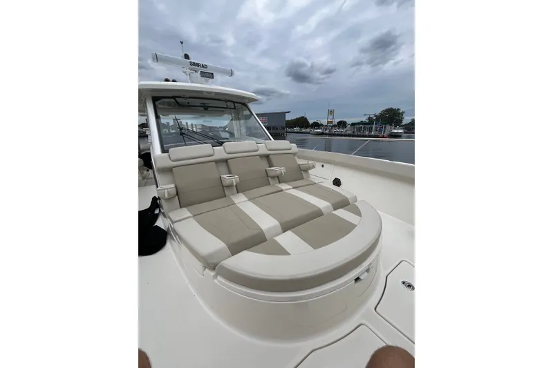 Slide: The Image of 2023 Boston Whaler 420 Outrage boat with cushioned seating, docked under cloudy skies. - 14