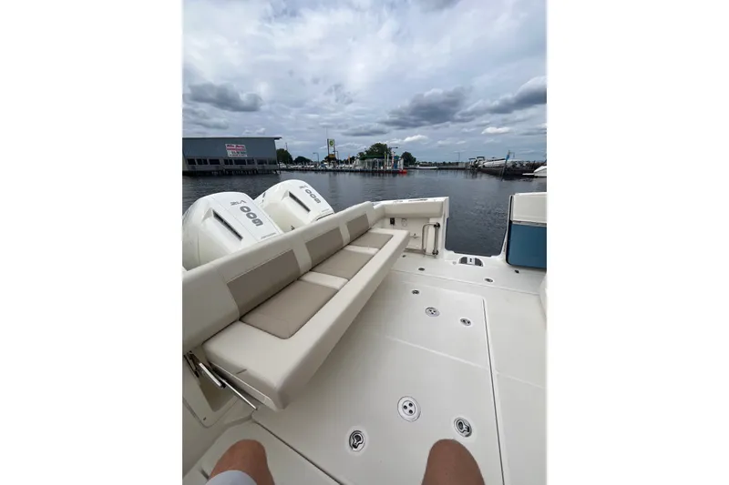 Slide: The Image of 2023 Boston Whaler 420 Outrage boat with seating, docked by a marina under cloudy skies. - 24
