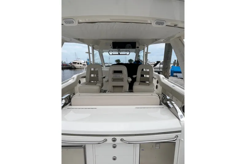 Slide: The Image of 2023 Boston Whaler 420 Outrage interior with seating and helm, docked at marina. - 21