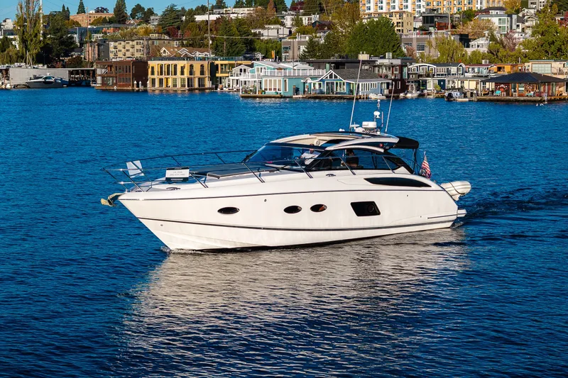 The Image of 2016 Princess V39 yacht cruising on a scenic lake with waterfront buildings. - 0