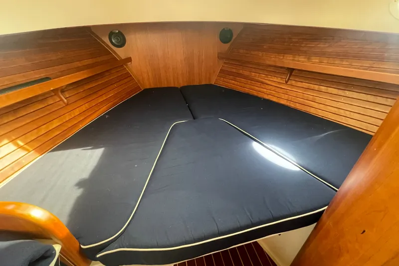 Slide: The Image of 2014 Hinckley Talaria 34 cabin interior with wooden paneling and dark cushioned bed. - 17
