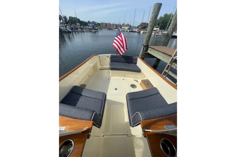 Slide: The Image of 2014 Hinckley Talaria 34 boat with seating, docked at a marina with American flag. - 4