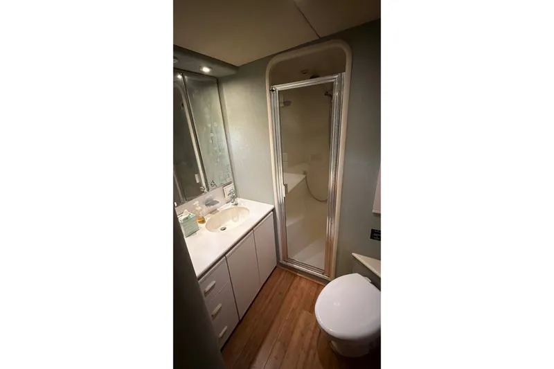 Slide: The Image of Bathroom interior of 1991 Bertram 60 Convertible yacht, featuring shower, sink, and toilet. - 19