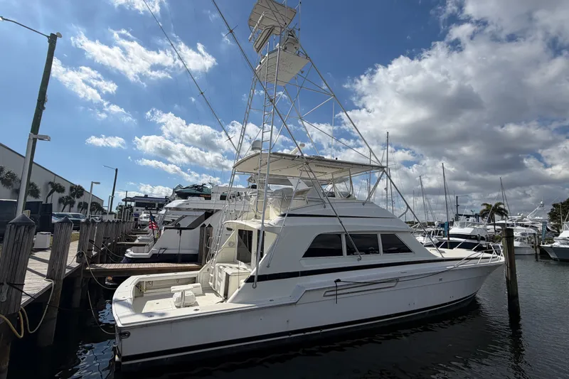 The Image of 1991 Bertram 60 Convertible yacht docked under a partly cloudy sky. - 2