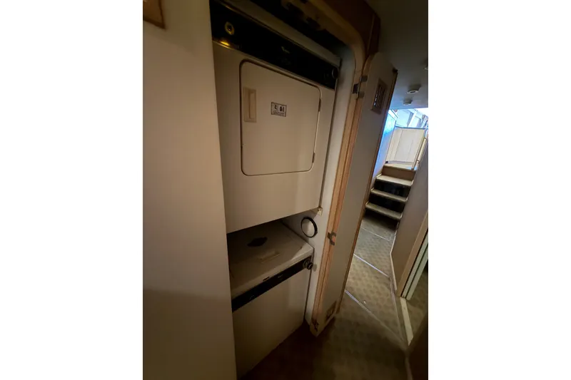 Slide: The Image of Laundry area inside a 1991 Bertram 60 Convertible yacht, featuring a stacked washer and dryer. - 16
