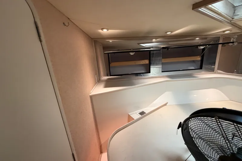 Slide: The Image of Interior of a 1991 Bertram 60 Convertible yacht, featuring windows and a fan. - 17