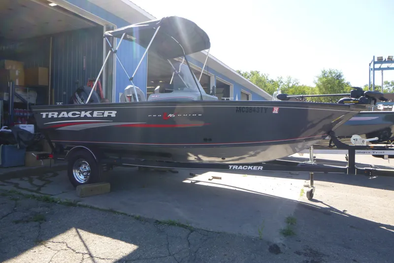 The Image of 2017 Tracker Pro Guide V-16 SC boat on trailer, parked outside a garage. - 1