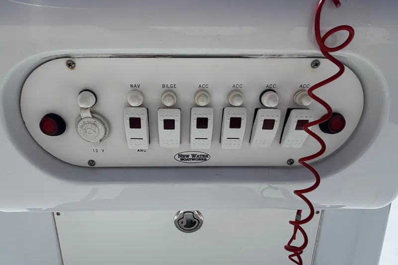 Slide: The Image of Control panel of a 2011 NewWater Ibis boat with switches and red coiled wire. - 13