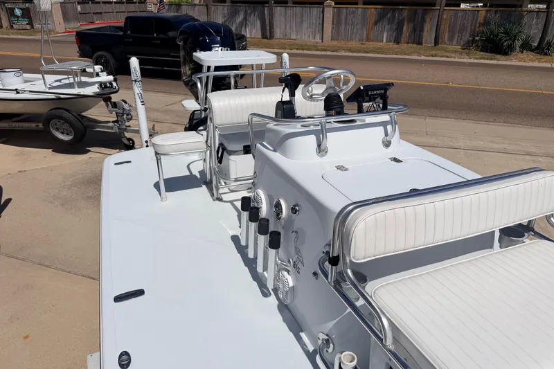 Slide: The Image of 2011 NewWater Ibis boat with white seating and steering console, parked near a road. - 24