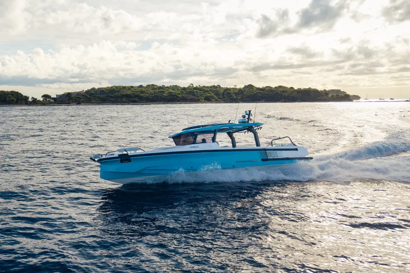 Slide: The Image of A 2027 Axopar 38 Cross Top boat cruising on the sea, surrounded by a wooded island. - 1