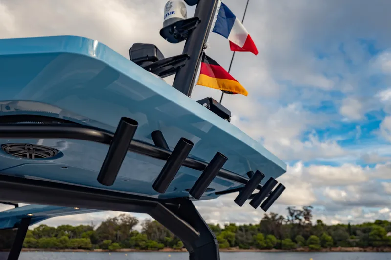 Slide: The Image of 2027 Axopar 38 Cross Top boat with flags, under a cloudy sky. - 14