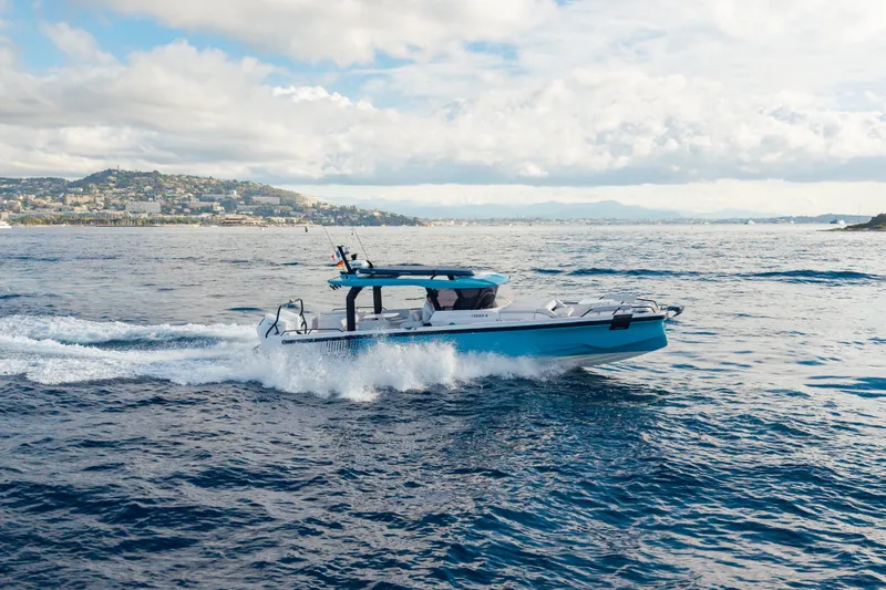 Slide: The Image of 2027 Axopar 38 Cross Top cruising on open water with scenic coastal backdrop. - 8