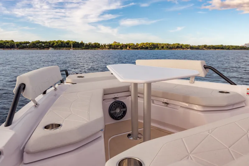Slide: The Image of 2027 Axopar 38 Cross Top boat interior with seating and table on calm water. - 20