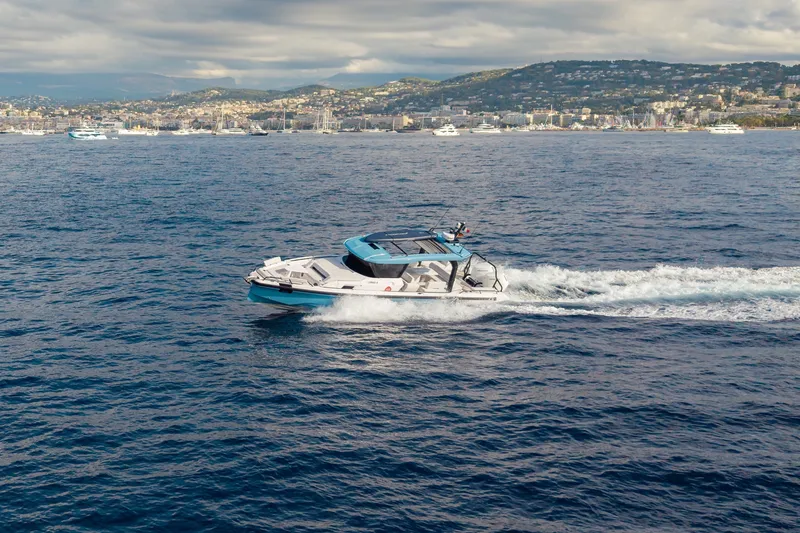 Slide: The Image of An Axopar 38 Cross Top boat speeds across the sea, with a city in the background. - 2