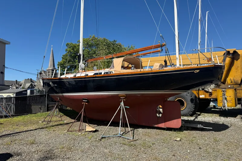 The Image of 1965 Hinckley Yachts Bermuda 40 sailboat on stands, displayed outdoors under clear blue sky. - 0
