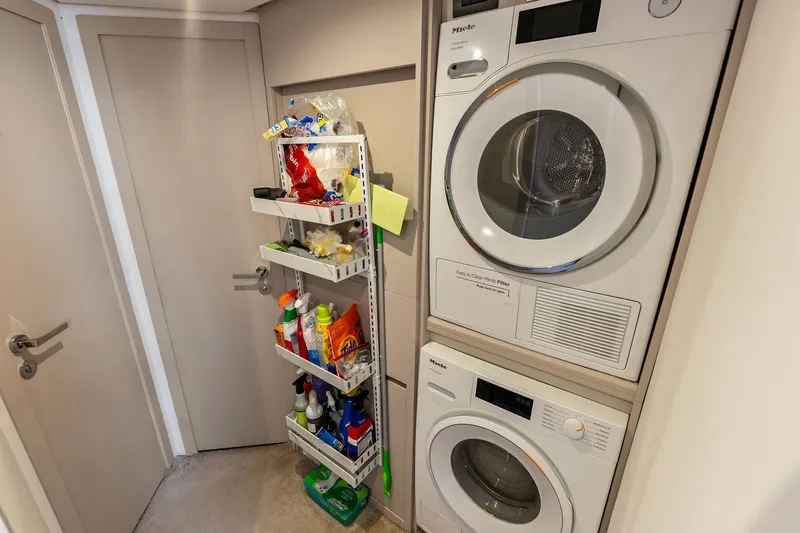 Slide: The Image of Laundry area on 2024 Ferretti Yachts 860 with stacked washer and dryer, storage shelves. - 105