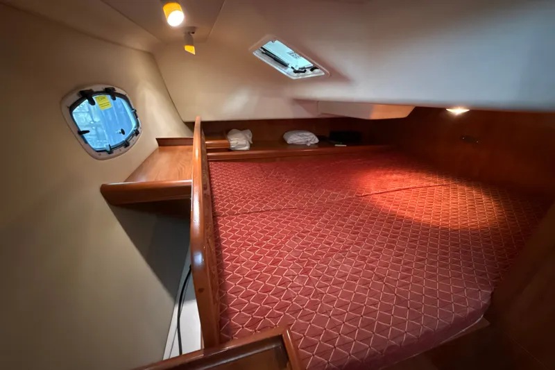 Slide: The Image of Cozy cabin interior of 2010 Hunter 36 sailboat with red bedding and wooden accents. - 13