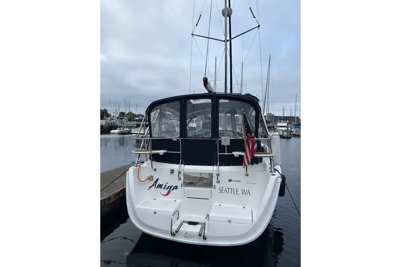 Slide: The Image of 2010 Hunter 36 sailboat docked in Seattle marina, rear view with canopy and American flag. - 42