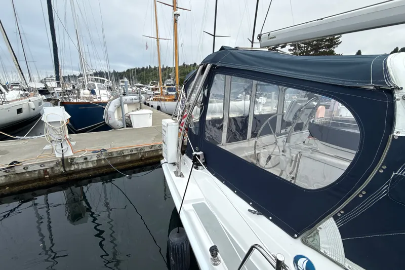 Slide: The Image of 2010 Hunter 36 sailboat docked at marina, featuring a covered cockpit and steering wheel. - 30